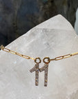 A close up detailed photo of the 11 diamond pendant, attached to a paperclip chain. In the background is a white quartz crystal.