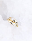 A pair of solid 14k yellow gold huggies, featuring a singular bezel set diamond, against a white background.