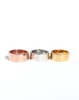 Three cigar bands stacked in order of silver, gold, and rose gold plating, all with a hammered texture.