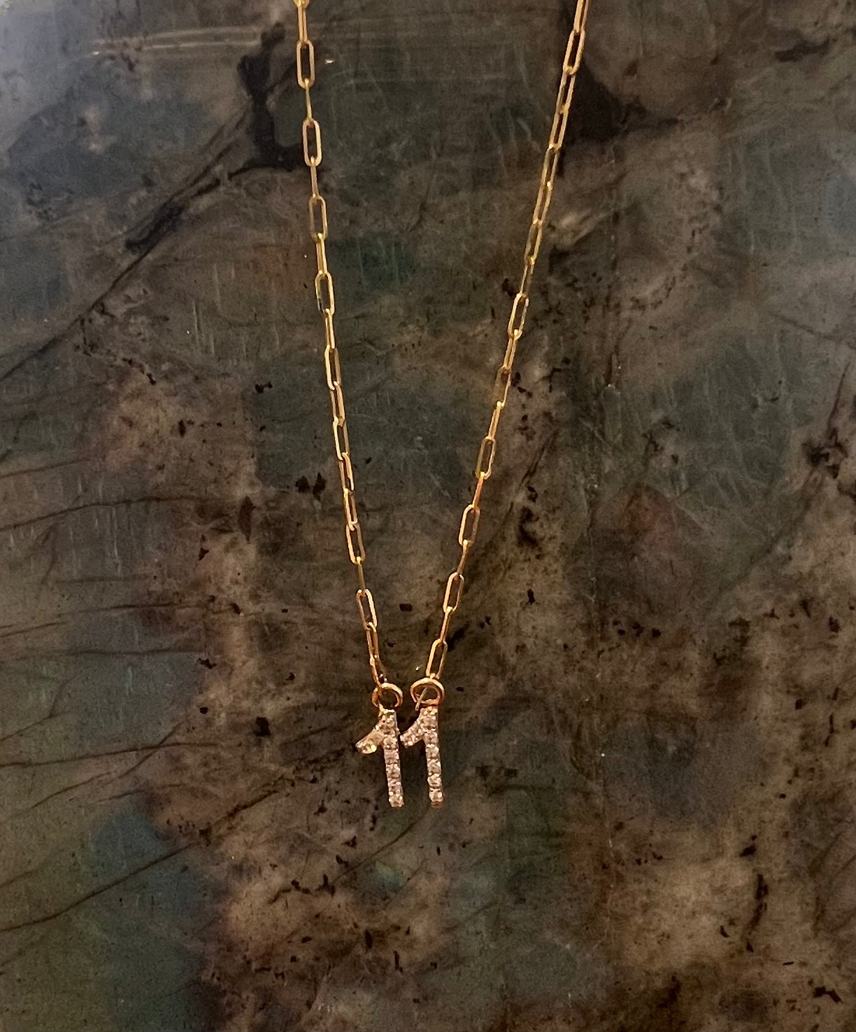 Solid 14k gold paperclip chain necklace with a small diamond 11 pendant at the center. Against a labradorite crystal. 