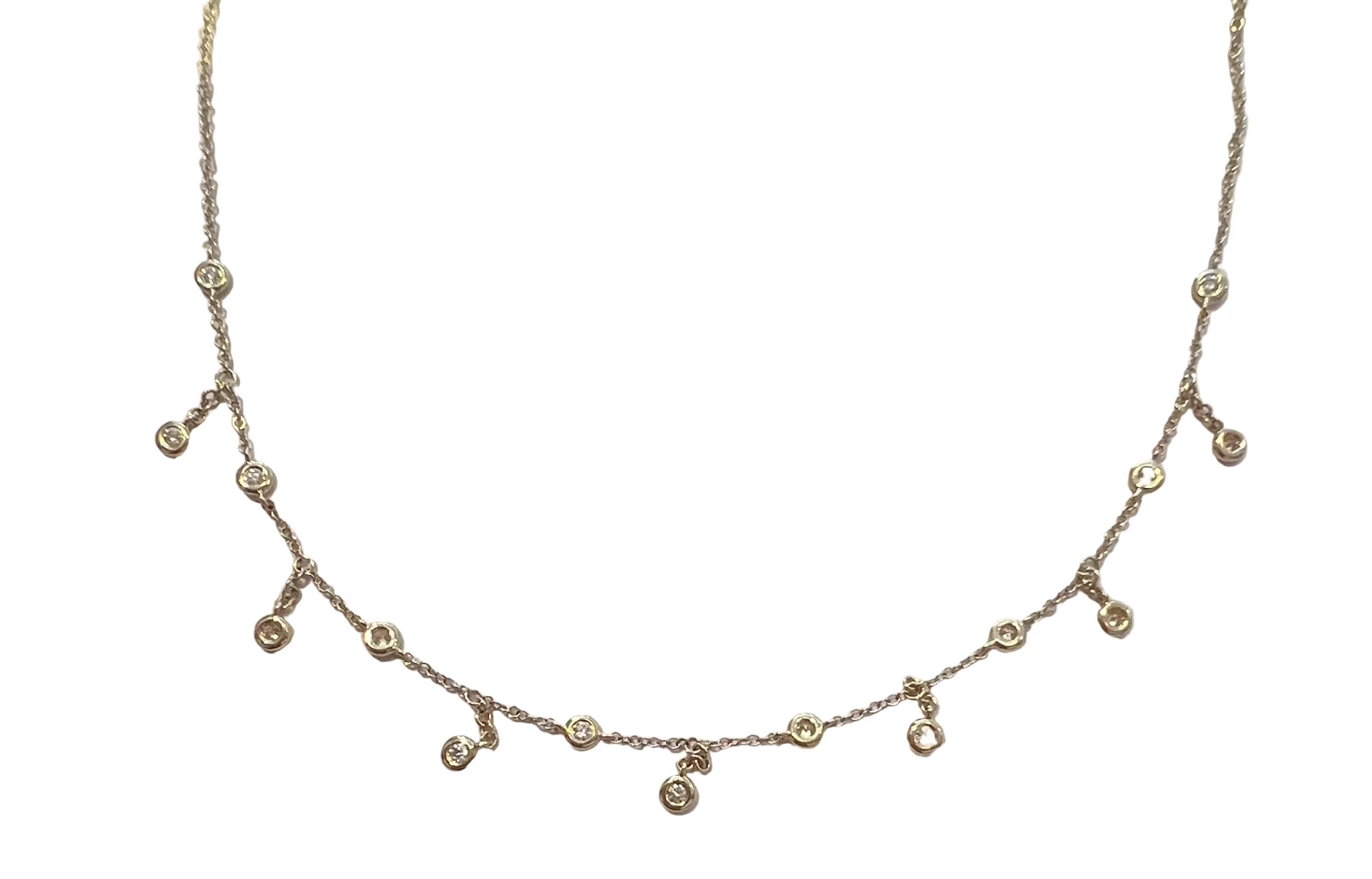 A delicate 14k yellow gold chain necklace with diamonds stationed apart, and in-between each diamond another diamond dangles down, on a white background