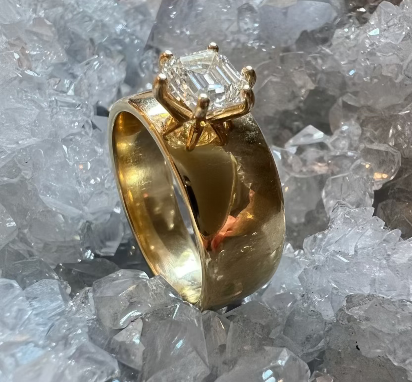 A side view of the 14k yellow gold ring with a prong-set hexagon diamond, showing off the thickness of the band, with a crystal background.