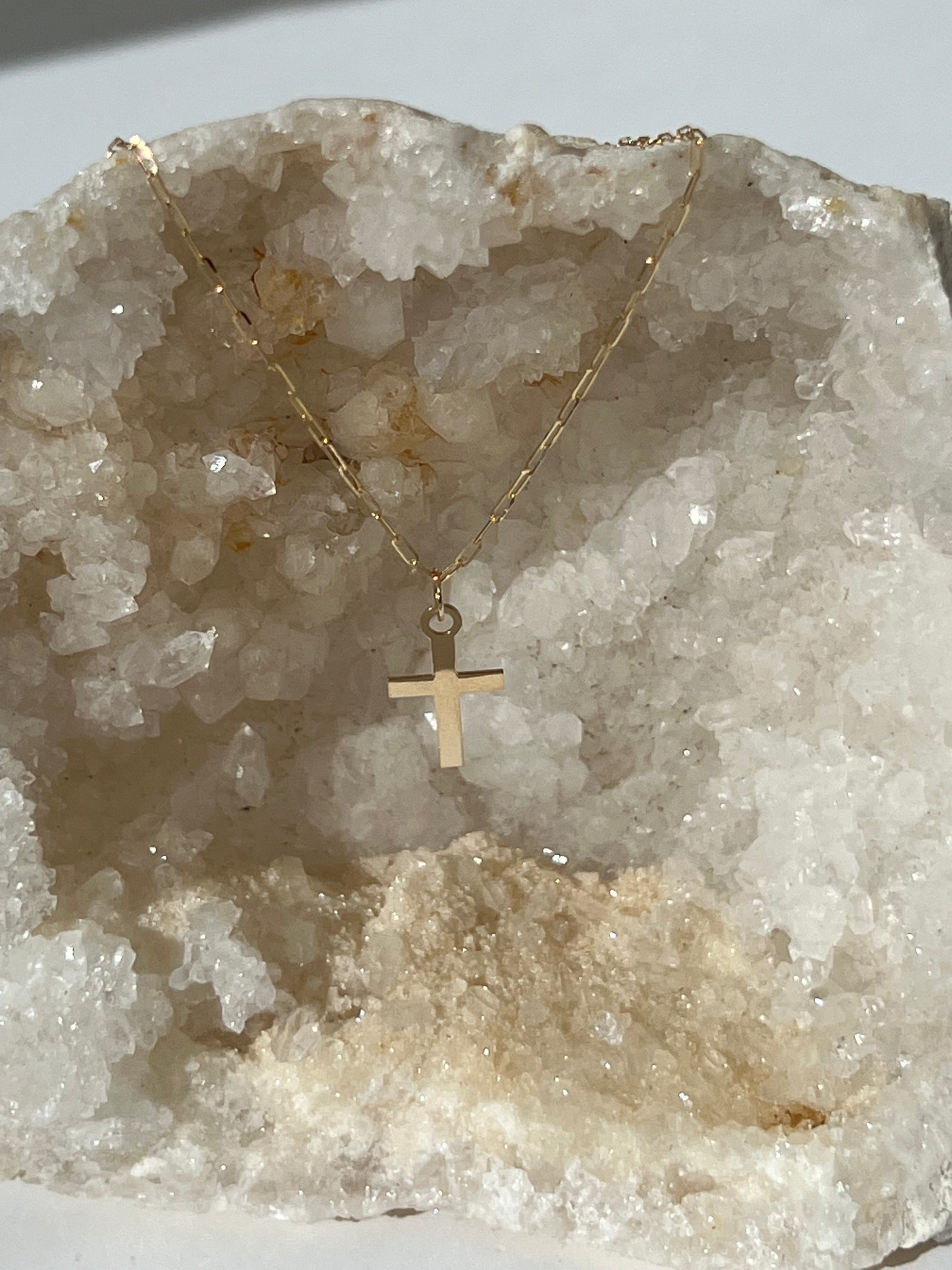 14k gold square cross pendant on a 16 inch paperclip chain, with a white crystal in the background.