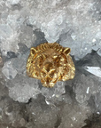 Front view of the face of the lion in the Aslan King of Beasts Gold Vermeil Lion ring. Showing the detail in the face and mane, and powerful gaze. Against a crystal background.