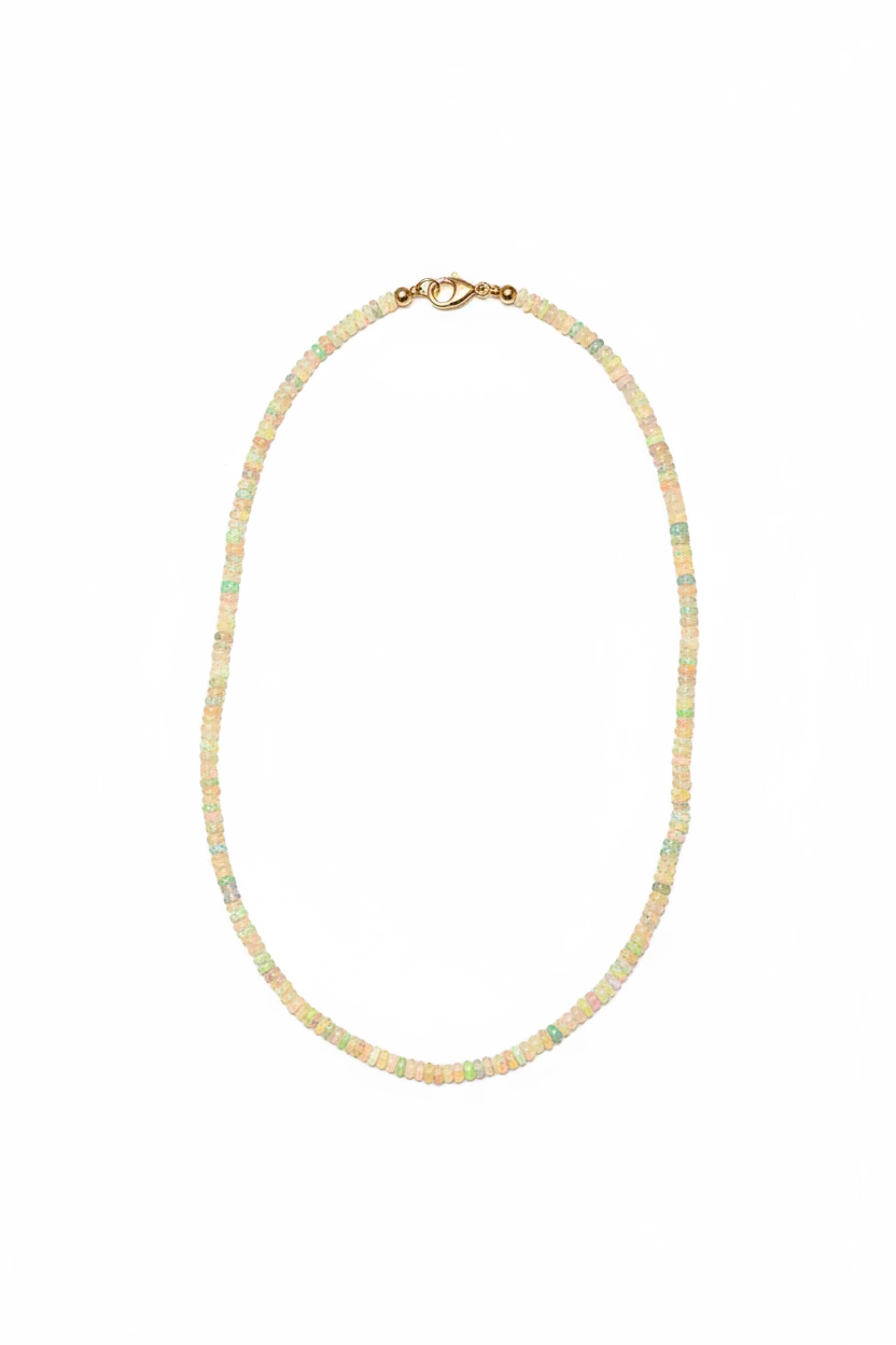 A delicate opal beaded necklace with a small gold lobster clasp, with a white surface