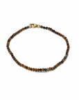 A dainty beaded bracelet with dark brown and black Tiger's Eye round beads and a small gold-filled clasp, resting on a white background.