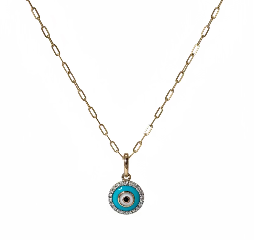 A 14k gold box chain necklace with an evil eye pendant made of gold, turquoise, diamonds, onyx to offer protection and spiritual meaning displayed on a crystal surface.