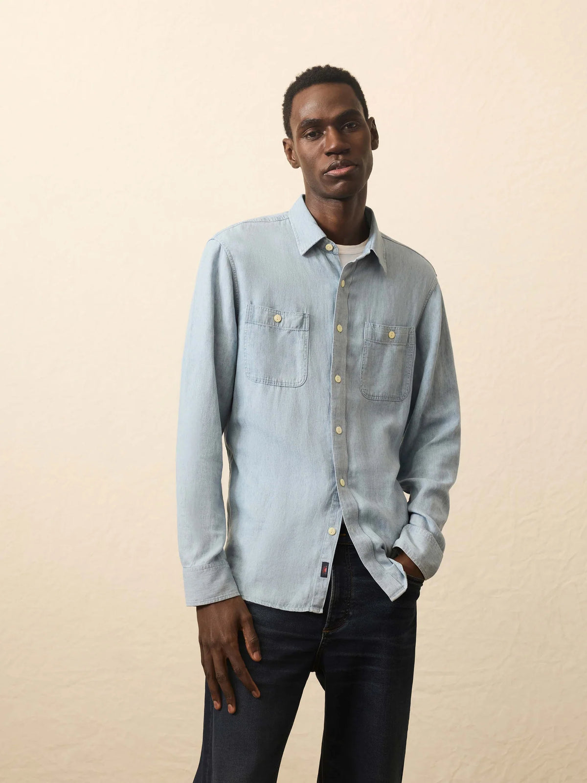 Man wearing a light blue denim shirt against a beige background