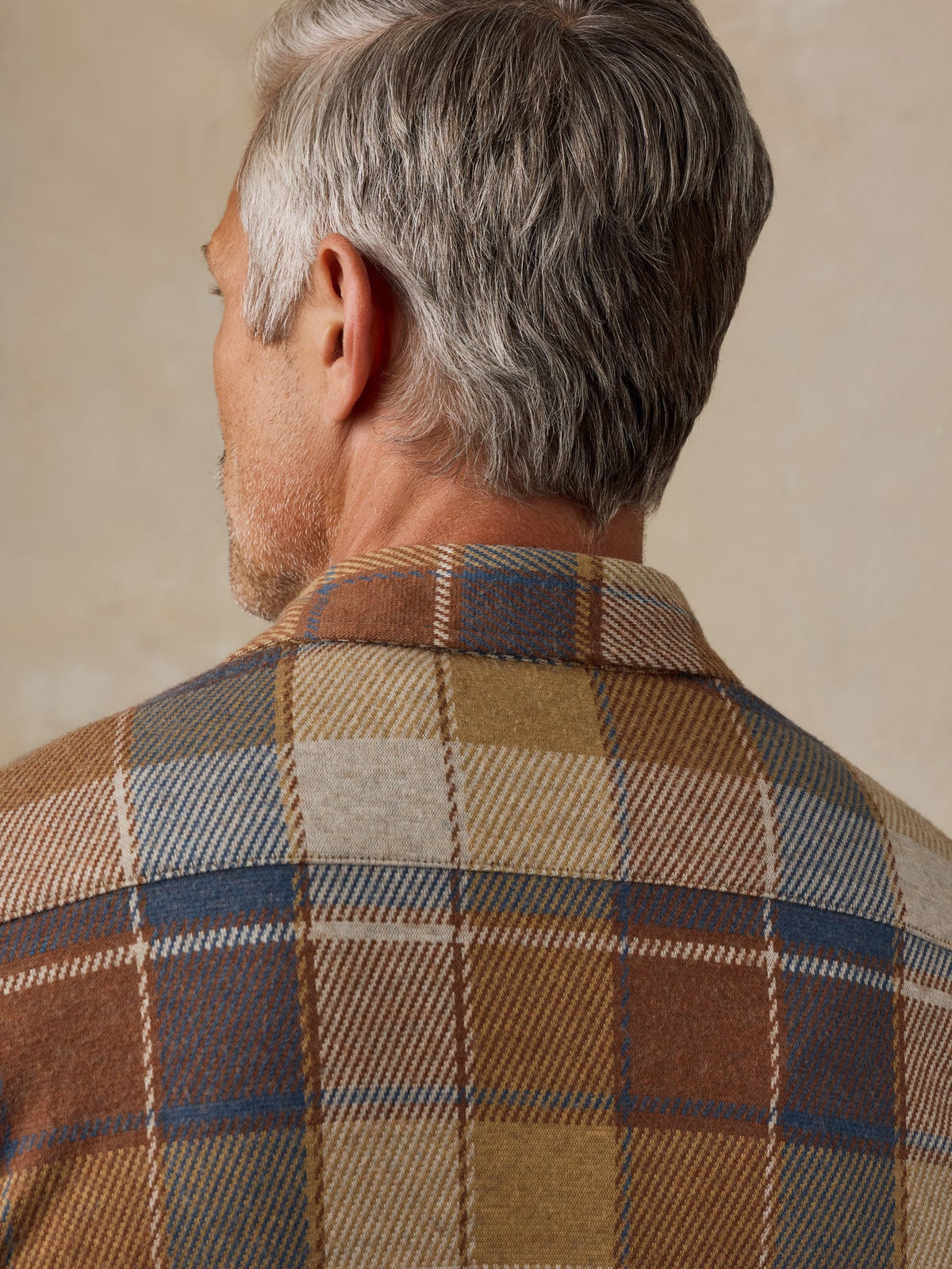A detailed shot of the collar from behind of a blue, grey, beige, brown, and redish plaid button down shirt. It is the Faherty Legend Sweater Shirt in boulder creek plaid. 