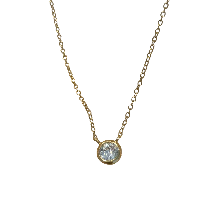 A delicate gold vermeil chain necklace with a single bezel-set clear gemstone pendant, on a white background. 