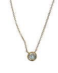 A delicate gold vermeil chain necklace with a single bezel-set clear gemstone pendant, on a white background. 