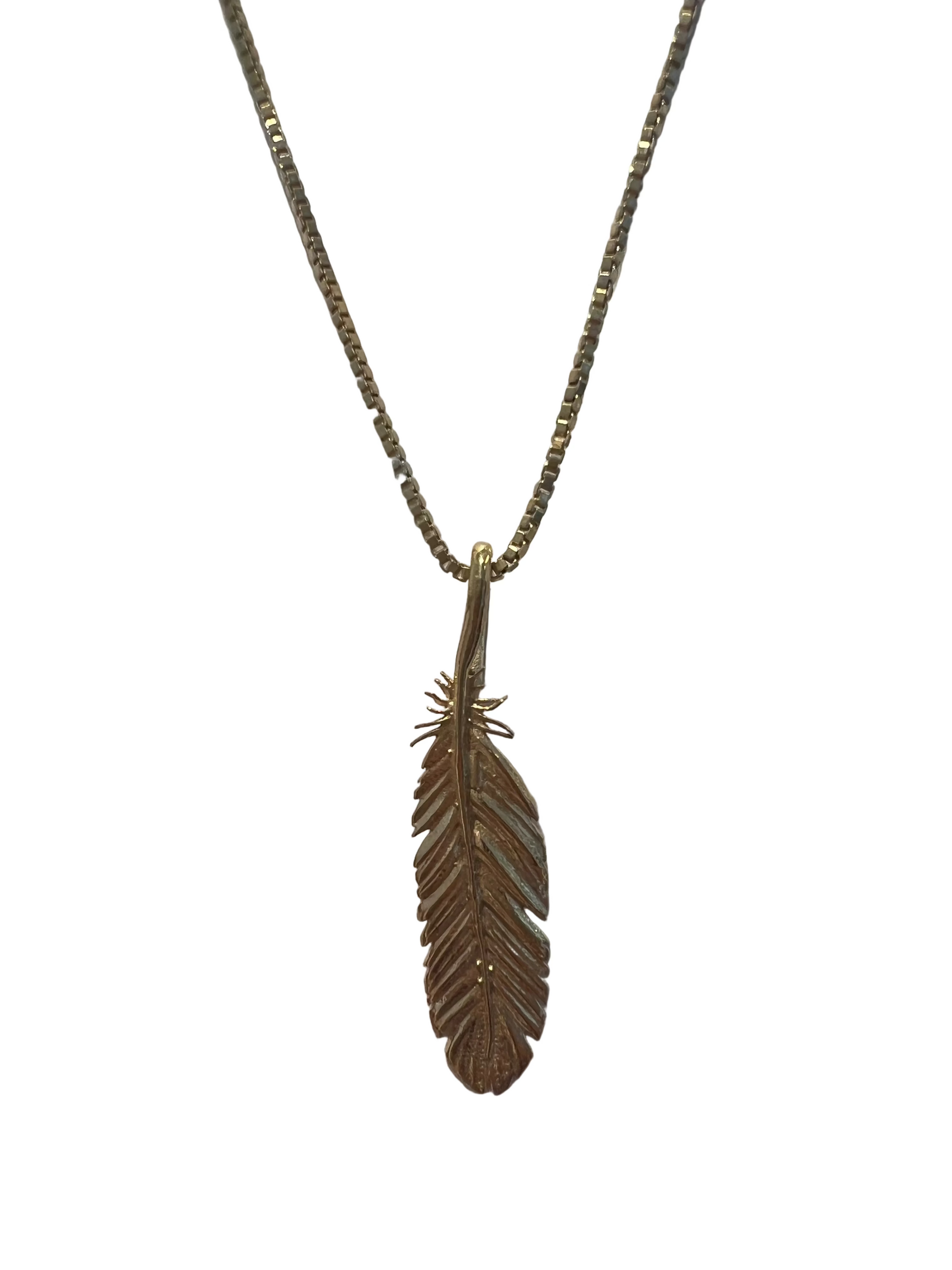 A gold vermeil (sterling silver plated in 14k yellow gold) necklace featuring a detailed feather pendant, displayed against a plain white background.