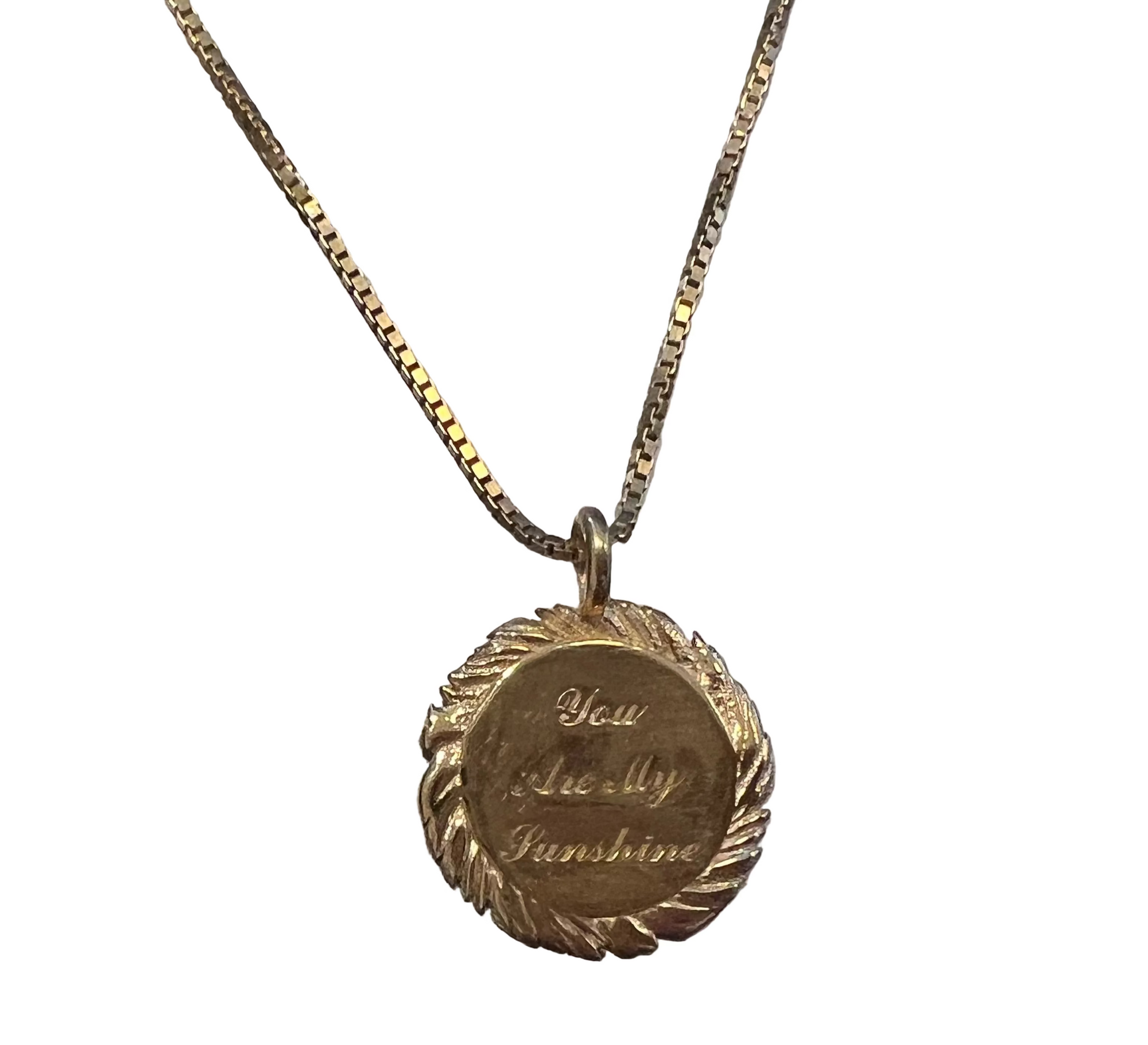 A gold vermeil pendant necklace with a round engraved medallion on a 16 inch gold box chain, displayed against a white background. The pendant features a wreath border and is engraved with the words 'You Are My Sunshine'.