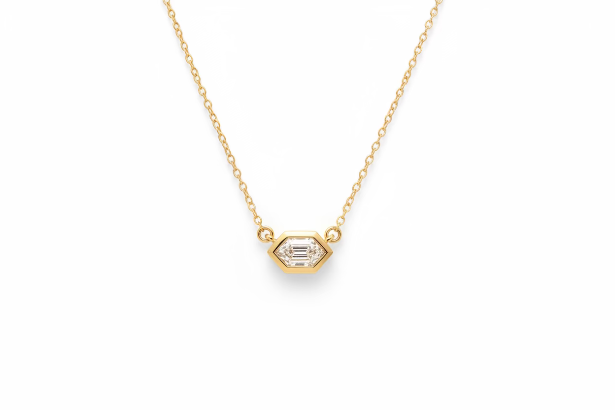 14k yellow hold necklace with a bezel set hexagon diamond. The diamond pendant is set securely at the center of a cable chain. The background is a quartz crystal.
