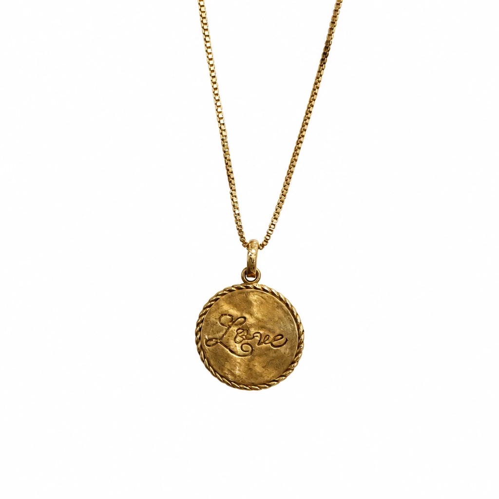 A gold vermeil necklace with a round pendant that spells out "love" in cursive on a white background.