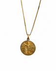 A gold vermeil necklace with a round pendant that spells out "love" in cursive on a white background.