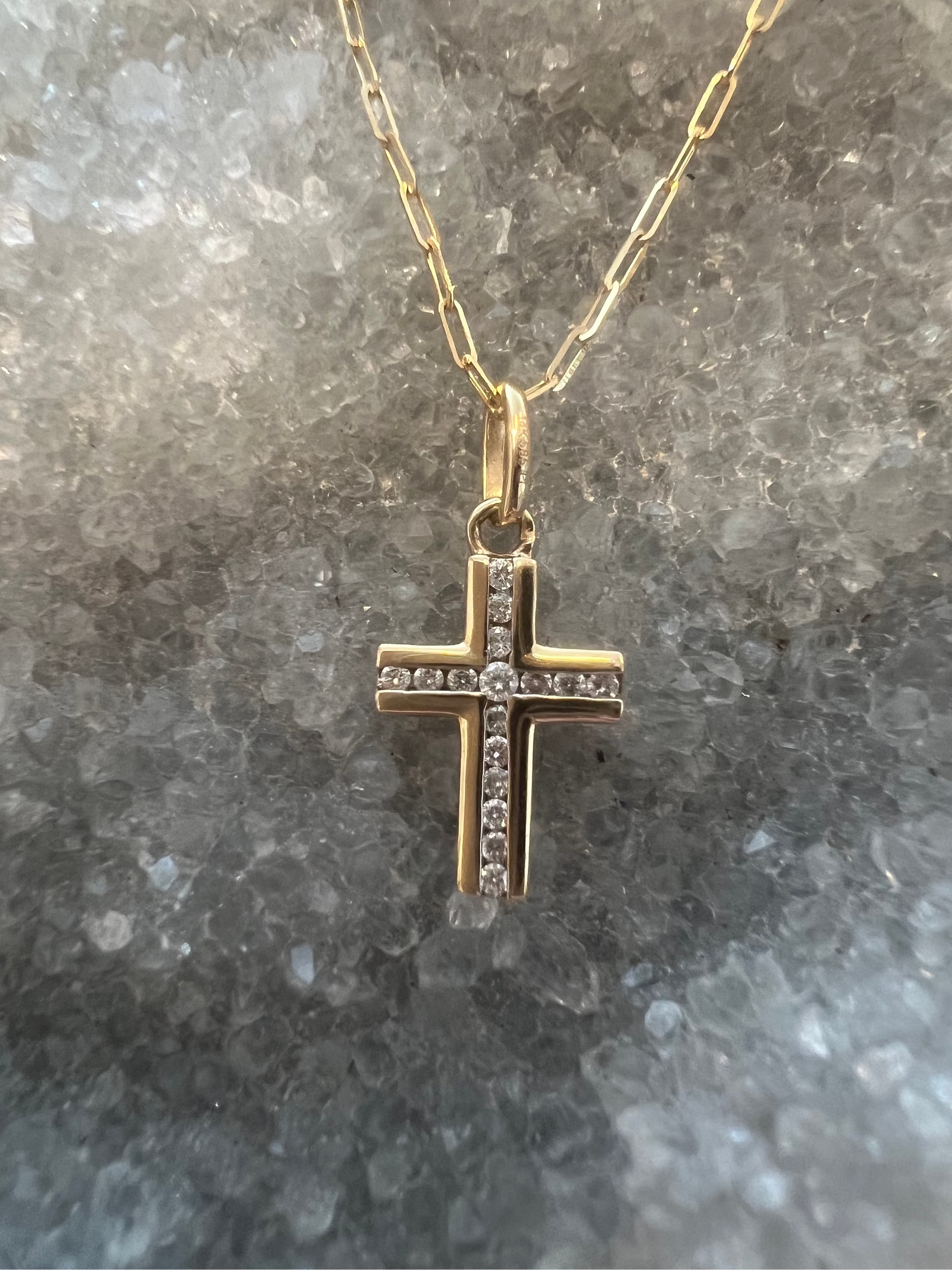 A solid 14k gold cross pendant necklace with 16 diamonds inlaid in the center, on a 16 inch paperclip chain necklace. 