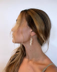 Wire wrapped pear dangle earrings displayed on a model, who has her head turned to the side. Against a white background. 