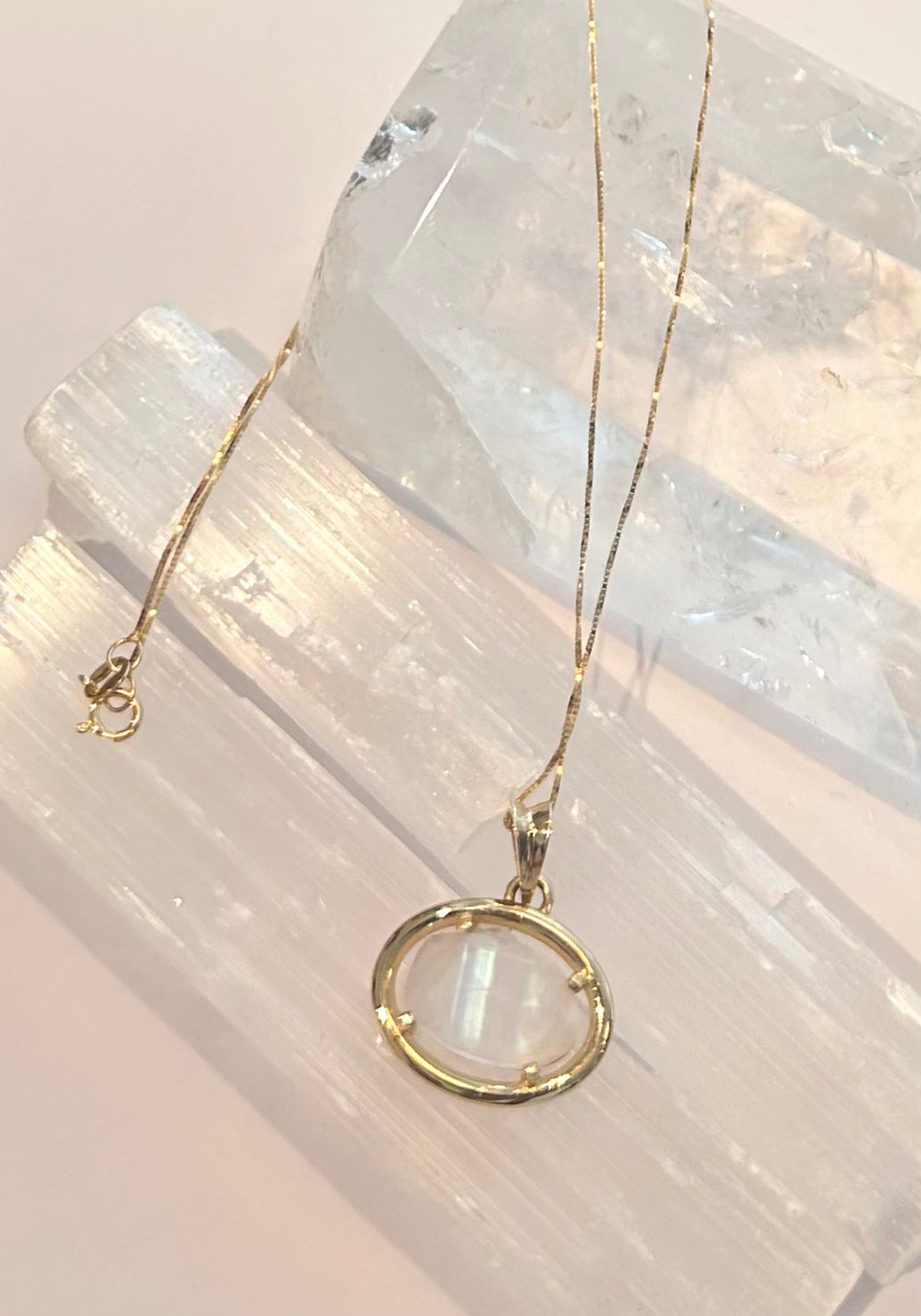 Solid 14k Gold necklace with a hand-carved moonstone pendant on a crystal background