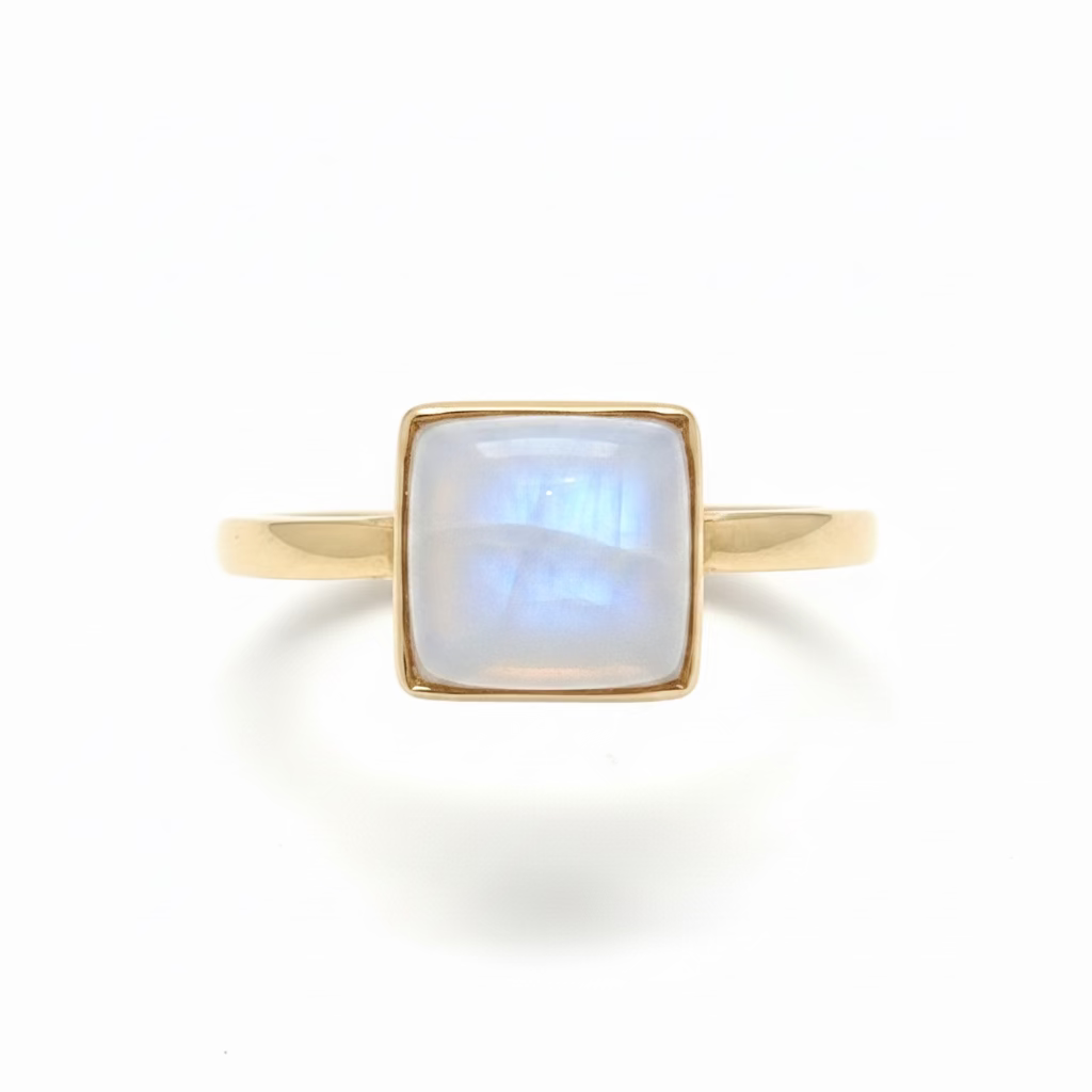 A square-cut moonstone gemstone ring with a 14k gold setting and band, displayed on a white surface.