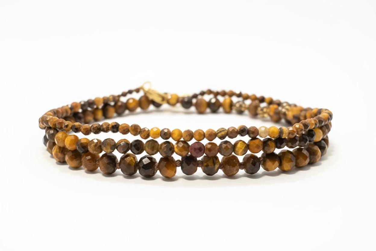 Three Tiger's Eye bracelets stacked on top of each other to show the varying sizes. Large beads are on the bottom, medium in the middle, and dainty on the top. Against a white background. 