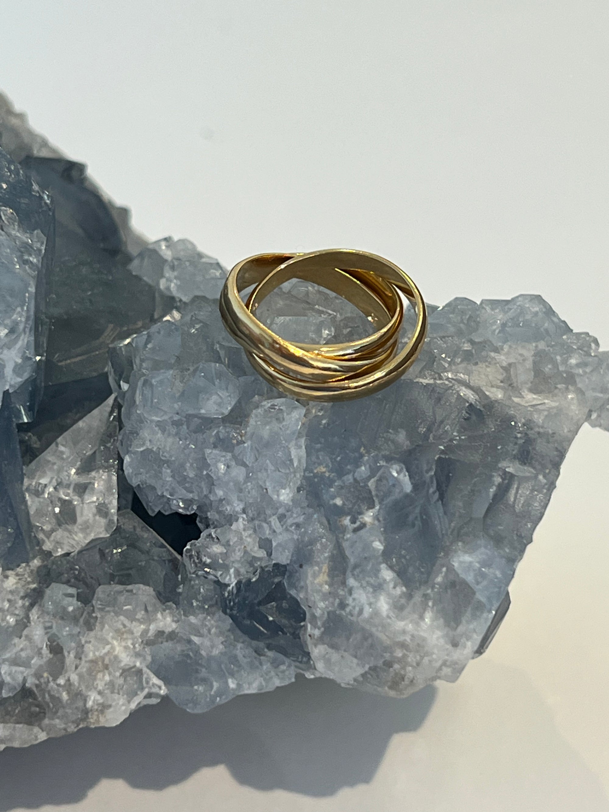 A gold vermeil braided inter-locking ring on a crystal surface.