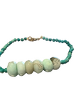 A beaded bracelet with turquoise green round beads and five larger marbled pale green chrysoprase beads, displayed against a white background.
