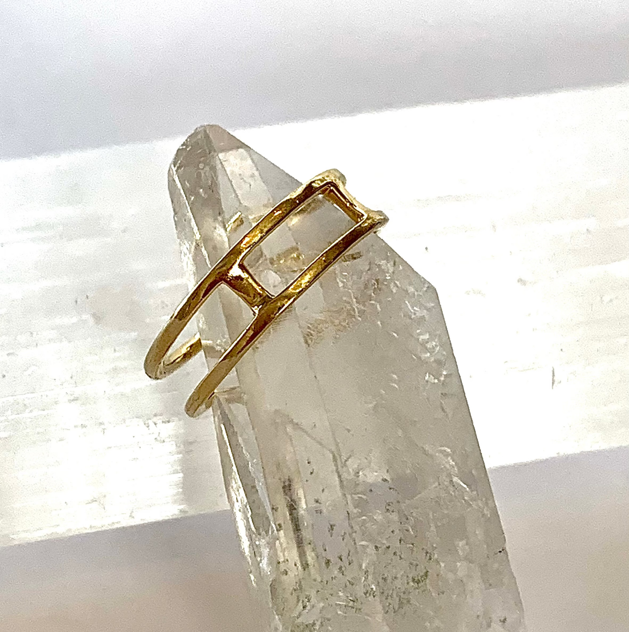 The back side of a solid 14k gold double diamond band ring. Showing the bars that secure the bands into place, allowing for the double band look, while maintaining space and placement, displayed on a crystal background. 
