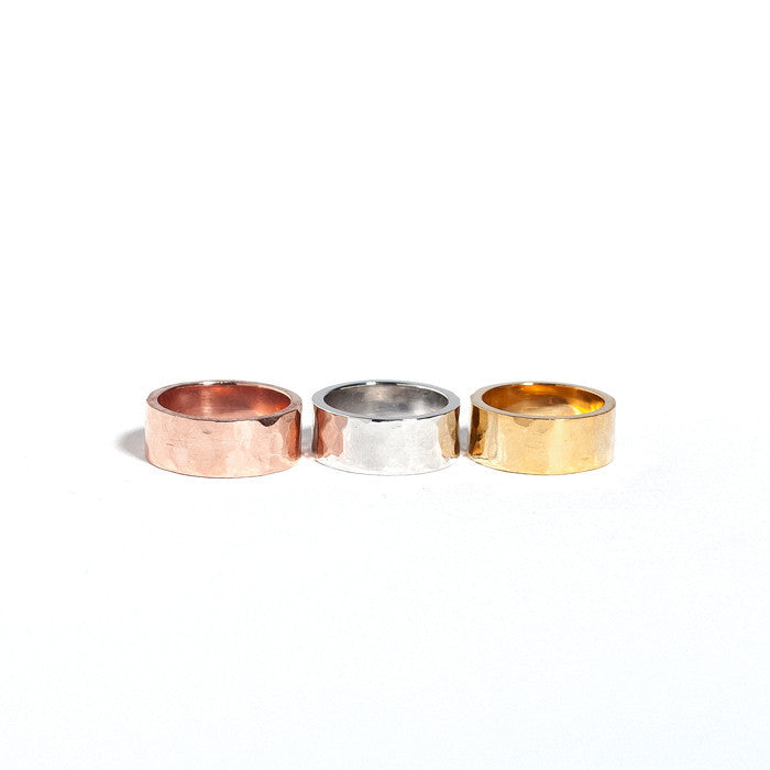 Three cigar bands stacked in order of silver, gold, and rose gold plating, all with a hammered texture.