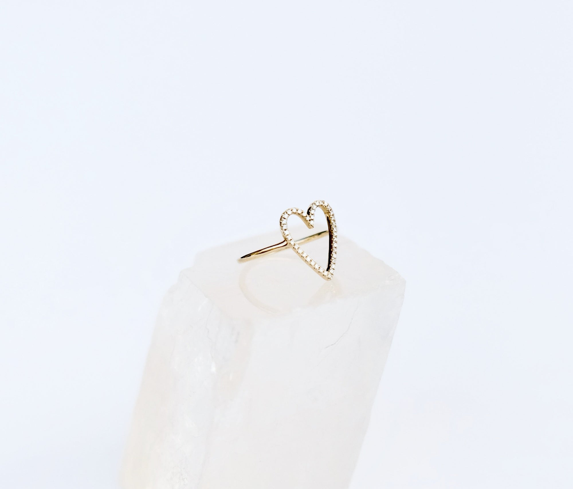 Solid 14k yellow gold halo heart outline diamond ring in size 6, on a quartz gemstone. This side view shows the thin band going around the sides of the heart. 