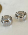 A pair of silver earrings with a heart-shaped design made from Cubic Zarconia Crystal this hypo-allergenic earring is displayed quartz plate.